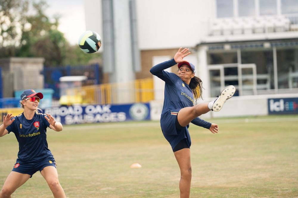 Two soccer players on a grassy field practicing ball control techniques during a training session.