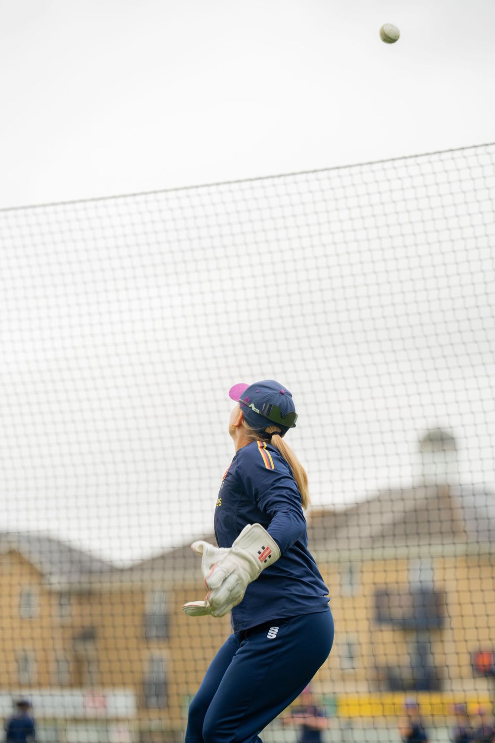 Sequence of soccer goalie diving to catch a ball against a white net background in navy blue uniform.