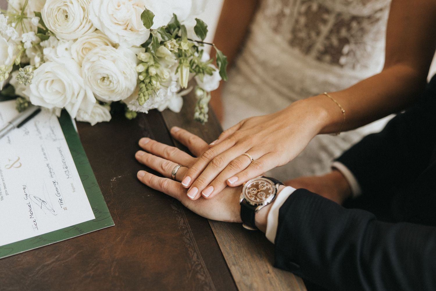 Close up shot of hands near white flowers and papers during wedding preparation.