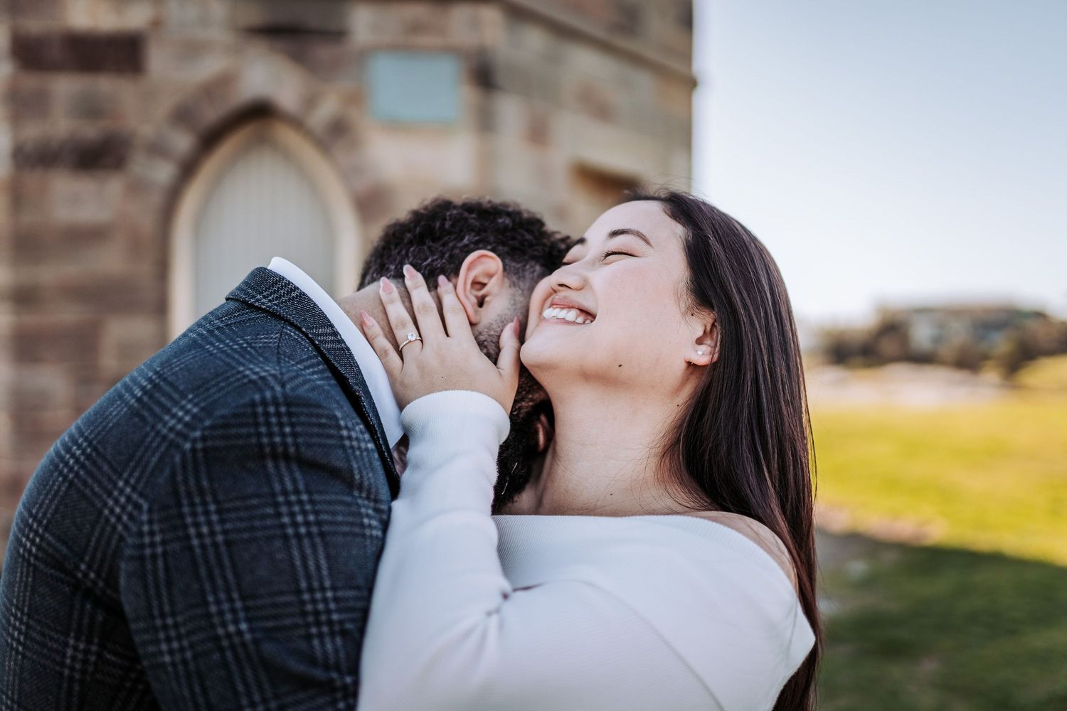 Two people share an intimate moment among stone architecture at golden hour in a romantic outdoor setting.