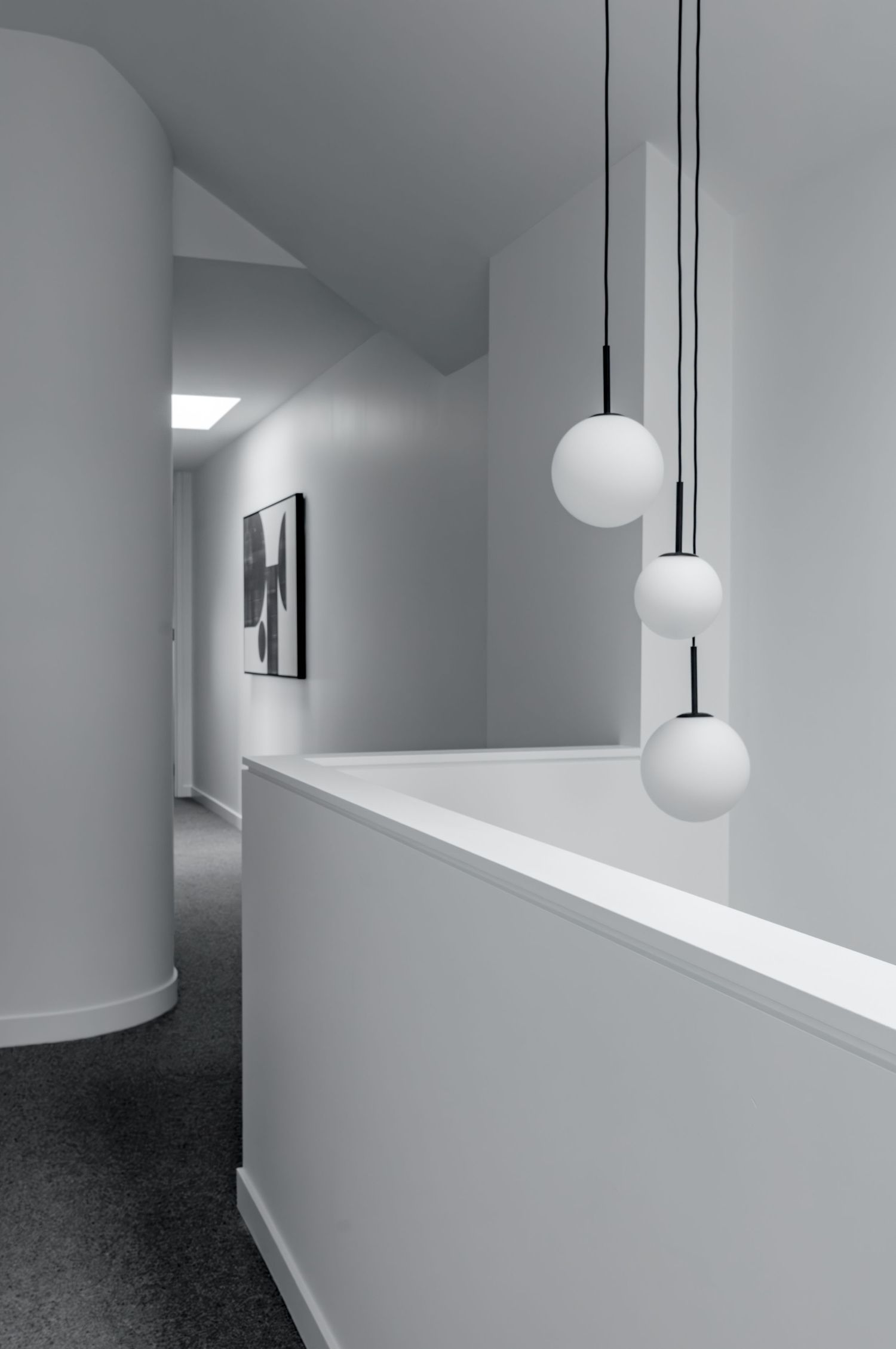 Modern white corridor with round pendant lights and curved wall details creating a clean architectural aesthetic.