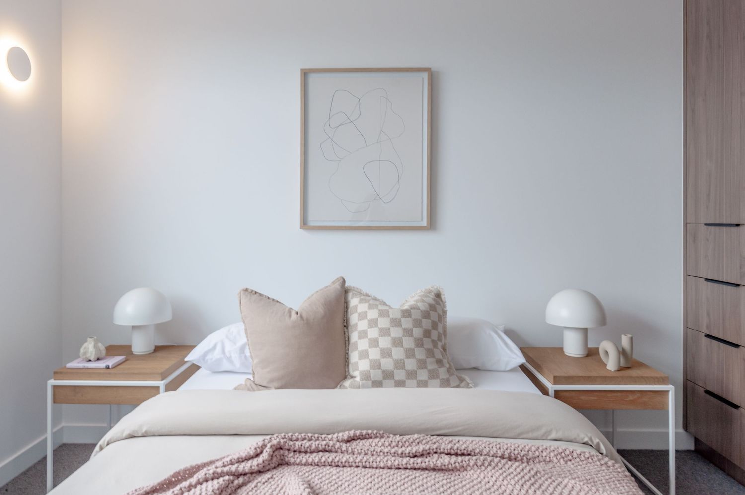 Modern Scandinavian bedroom features light wood flooring, white walls, and minimalist furniture in neutral tones.