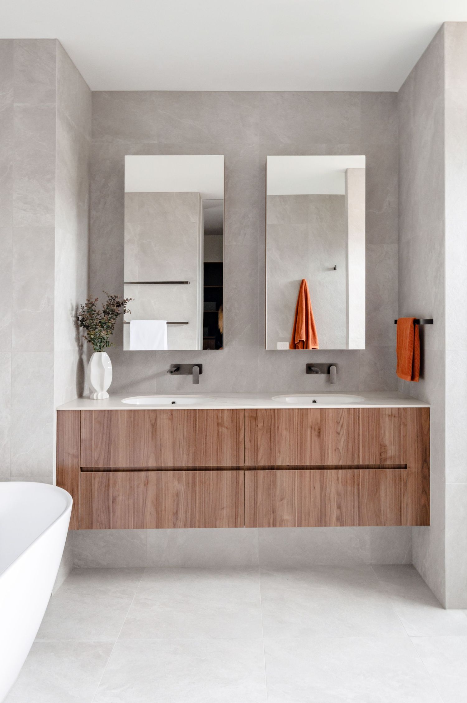 Modern minimalist bathroom design featuring floating wood vanity and square mirrors against concrete walls.