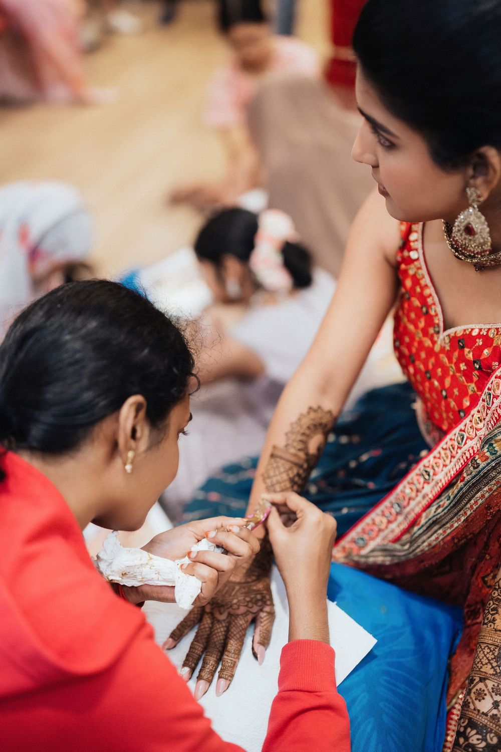 Hands covered in intricate henna designs being applied during traditional Indian wedding preparations.