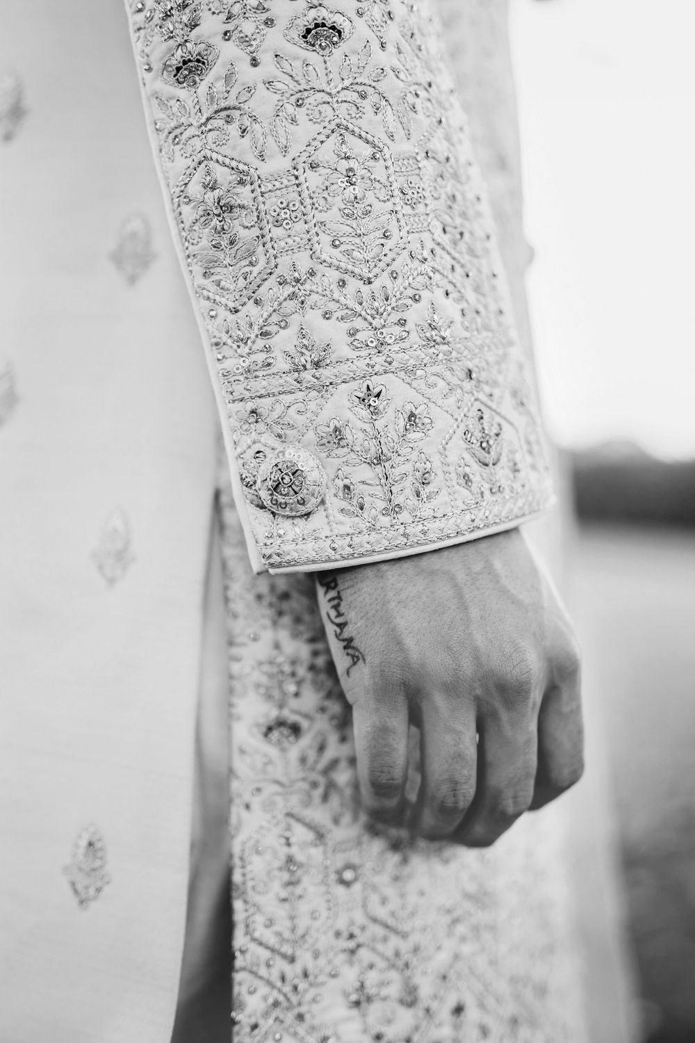 Close-up detail shot of intricate beaded lace pattern on white wedding dress sleeve.