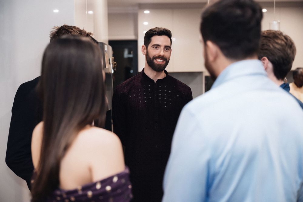 A group of people having a conversation in an indoor setting while standing in a circle.
