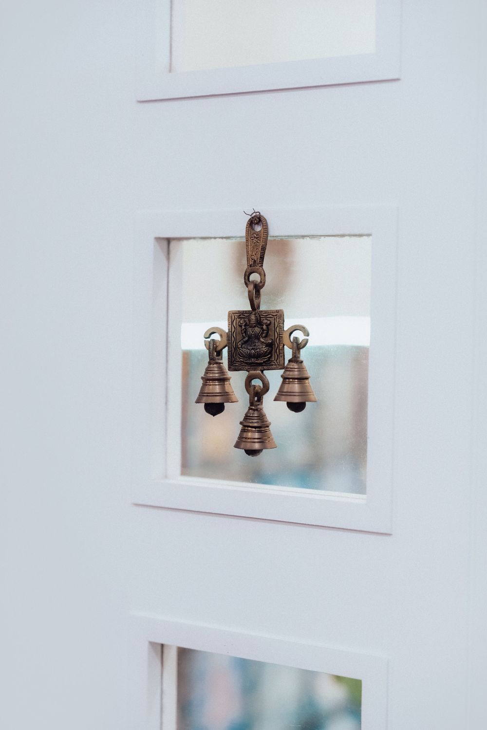 Decorative bronze bells hanging from a white door panel as traditional ornaments.