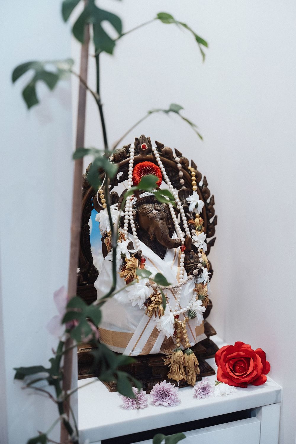 Three ornate holiday hair accessories with floral designs and ribbons displayed on white shelves against a white wall.