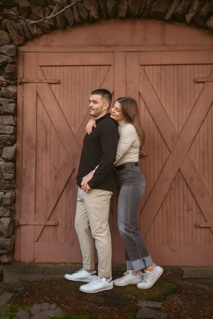 A couple posing playfully against a rustic wooden barn door.