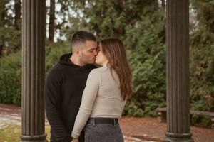 A romantic couple embraces while standing between stone columns during a sunset engagement photo session.