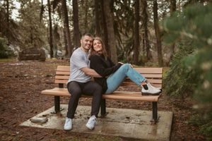 Happy couple sitting together on wooden bench in forest setting.