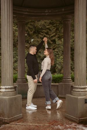 A couple dancing together in a romantic moment between stone pillars at a garden gazebo.