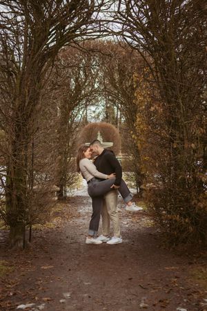 A couple shares tender moments along a wooded path covered in autumn leaves in sequential photos.