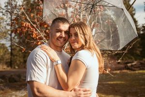 A romantic couple embracing in golden sunlight with autumn foliage in the background.