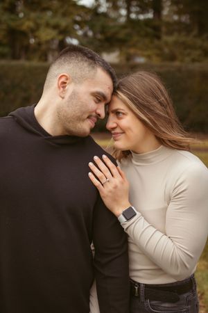Romantic engagement photo of couple in casual wear sharing an intimate moment outdoors.