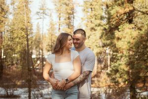 A tender embrace captured in golden sunlight with evergreen forest backdrop.
