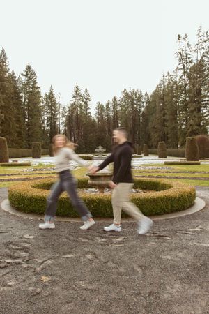 Motion-blurred photo of couple dancing and spinning in a garden with pine trees.