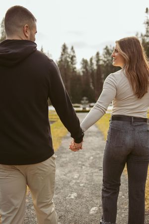 A couple in casual attire holding hands while standing together on an outdoor trail.