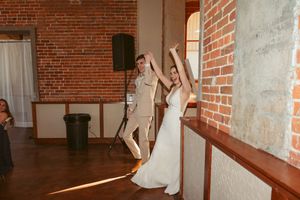 Dynamic dance performance in a sunlit brick-walled venue with large windows.