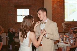 Dancers celebrating at a wedding reception in elegant formal attire inside a historic brick building.