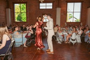 A couple performs their first dance at a wedding reception in a rustic brick venue.