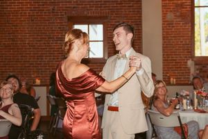 Wedding reception dance sequence in a sunlit brick venue with seated guests.