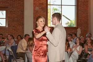 Reception guests watch a dance performance in a warm-lit brick venue with large windows.