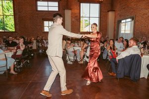 Elegant dance performance featuring a coral dress against exposed brick walls and brightened windows.