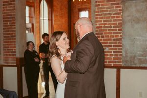 A couple dances together in an intimate moment during a wedding reception in a brick-walled venue.
