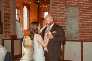 Couples dance at a wedding reception in an elegant brick-walled venue with ambient lighting.