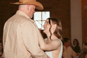 A tender dancing moment captured between a couple during their wedding reception in a rustic venue.
