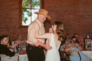 Dancers perform entertaining moves during a wedding reception in an industrial-style brick building.