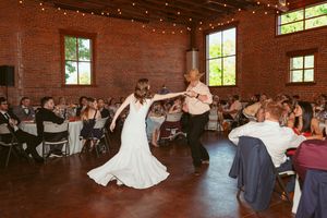 Wedding celebration with dancers performing in front of exposed brick walls under string lights.