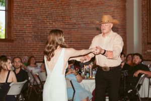 Dancers entertain wedding guests with spirited moves in a warmly lit brick reception space.