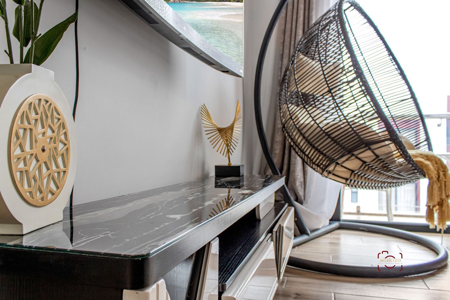 Modern loft-style living room features hanging egg chairs, wood accents, and sleek white decor with circular wall art.