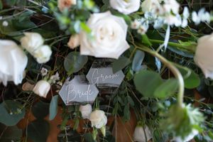 White roses and lush greenery create an elegant floral arrangement against a light background.