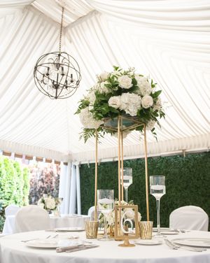 White draped tent ceiling with chandeliers and gold accents creates an elegant atmosphere for a luxury wedding reception setup.