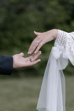 A series of hands adjusting a delicate white bridal veil in a romantic outdoor setting.