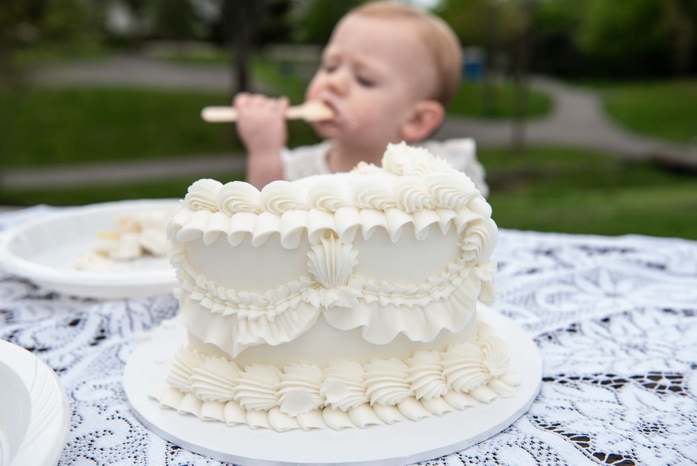 White tiered wedding cake on lace tablecloth with decorative ruffled details.