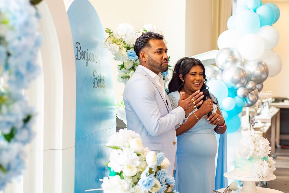 A couple celebrates their special moment under an elegant blue and white balloon arch with floral decorations.