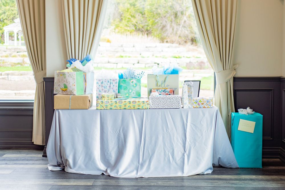 Baby shower gift table decorated in light blue and white with wrapped presents and party favors.
