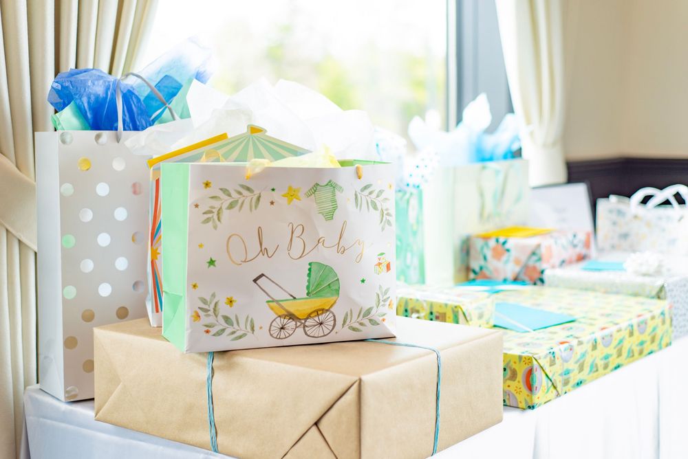 Baby shower gifts and presents wrapped in pastel colors with a stroller design card on display.