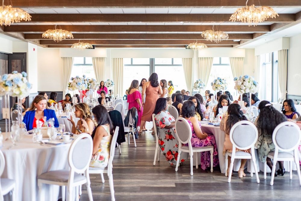 An elegant wedding reception in a bright banquet hall with crystal chandeliers, white tables and decorative chairs.