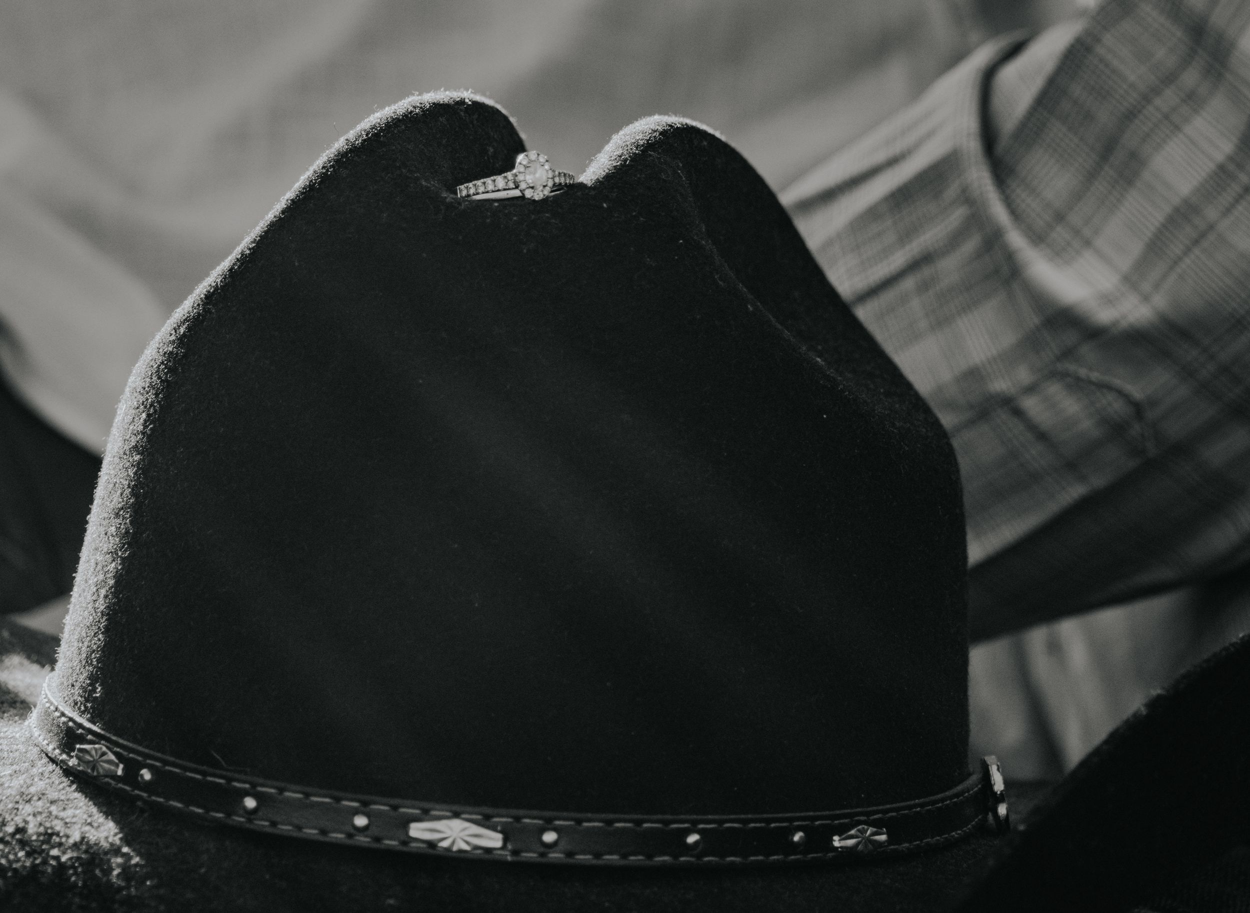 A black cowboy hat with a decorative band shown in a black and white close-up photograph.