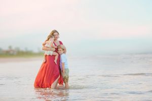 A tender moment between parent and child playing in shallow ocean waters at sunset.