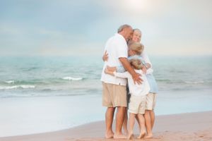 Sweet family moment captured on beach with ocean waves in background.