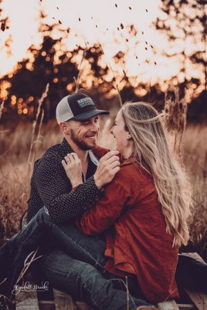 Couple sharing intimate moment in field during golden sunset.