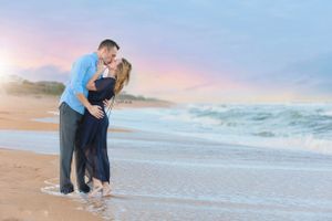 Romantic couple embracing on beach during sunset with waves in background.