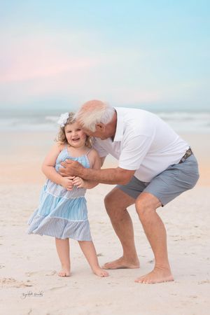 Heartwarming beach moment captured during sunset with soft pastel sky.