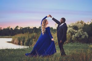 Couple dancing in formal wear by lakeside during twilight.